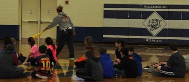 Students sitting on gym floor in gym class